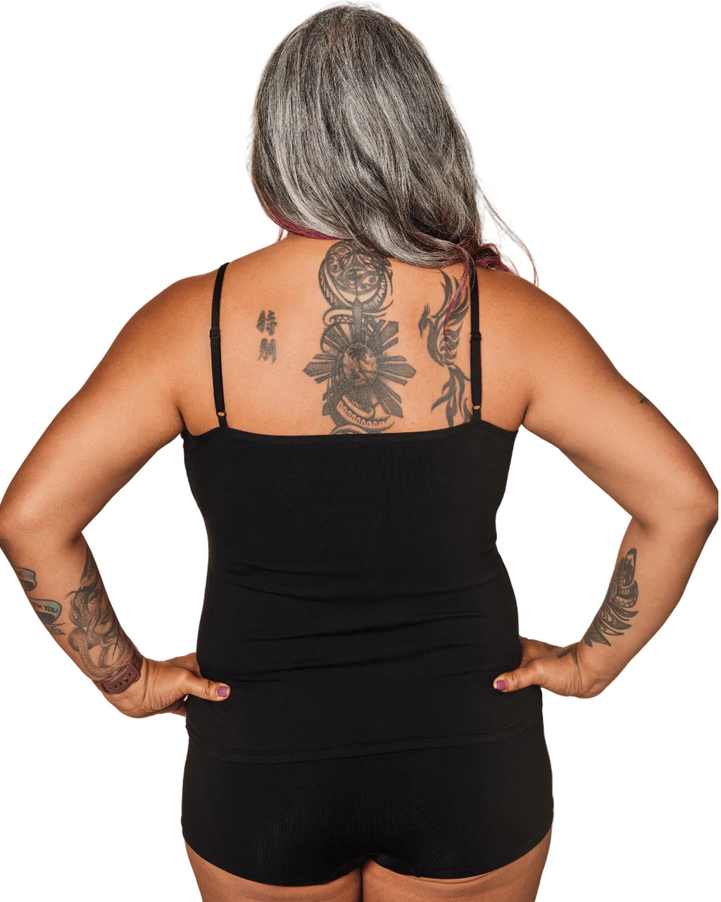 Person wearing a black tank top and shorts with visible tattoos on a white background