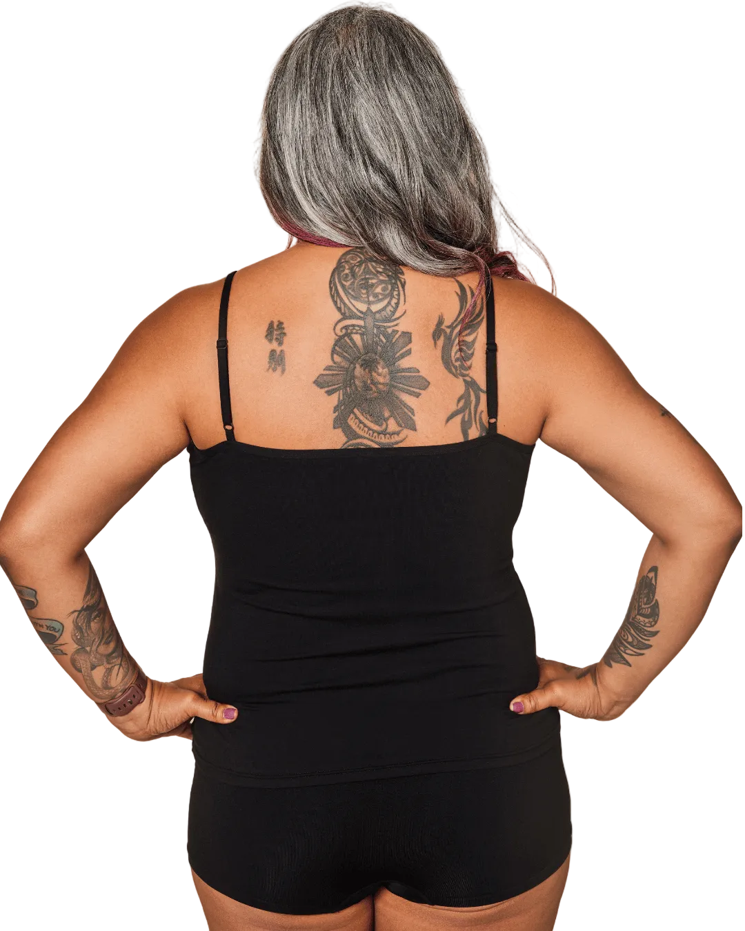 Person wearing a black tank top and shorts with visible tattoos on a white background