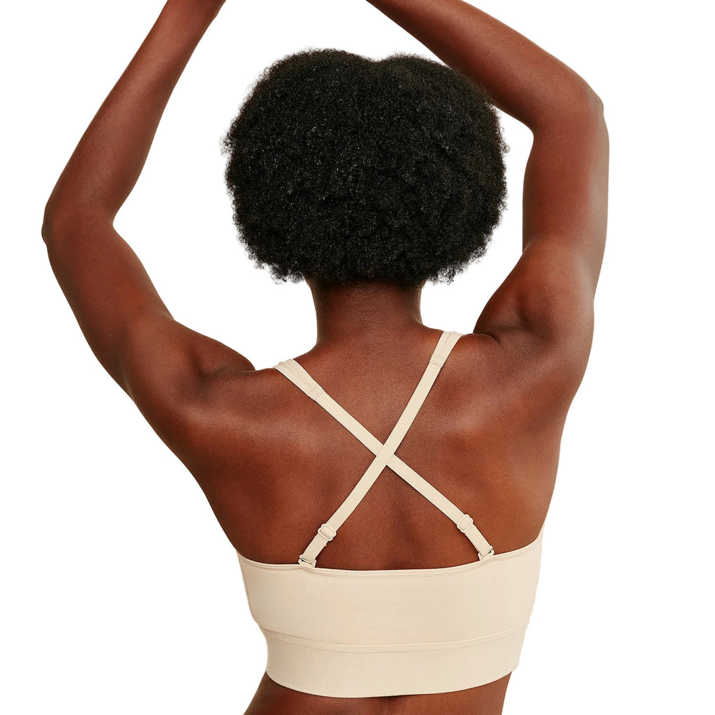 Person wearing a beige sports bra with criss-cross straps on a white background